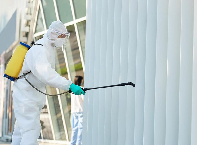 A pest control technician spraying the exterior of a building